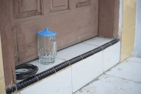 An empty glass cup placed in front of a closed house door Stock Photos