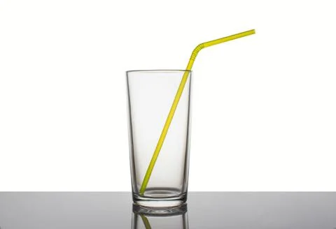 Empty glass cup with a straw for drinks on a white background Stock Photos
