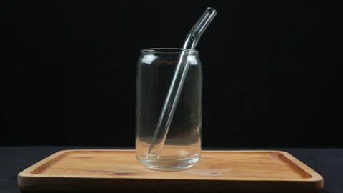 Empty glass cups and straws on wooden tray isolated on dark background Stock Photos