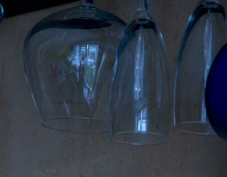 Empty glass goblets of different sizes hanging upside down Stock Photos