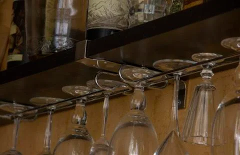 Empty glass goblets of different sizes hanging upside down Stock Photos