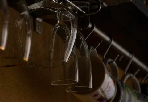 Empty glass goblets of different sizes hanging upside down Stock Photos