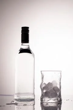 Empty glass with ice cubes and bottle Stock Photos