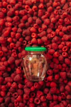 Empty glass jar for raspberry cooking, on the texture of red ripe raspberr... Stock Photos