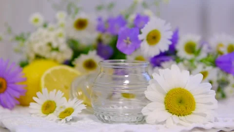Empty glass jar surrounded by chamomile flowers and wildflowers on bright Stock Footage 346184913