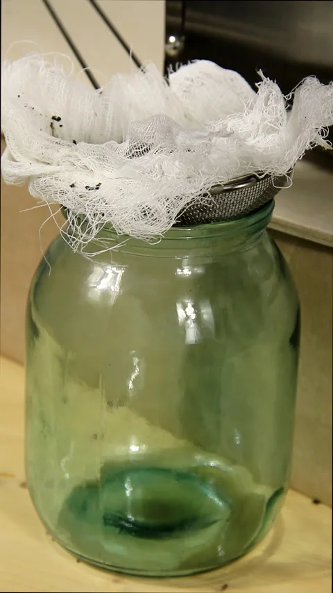 An empty glass jar into which squeezed vegetable oil begins to drip. Stock Footage 168889433