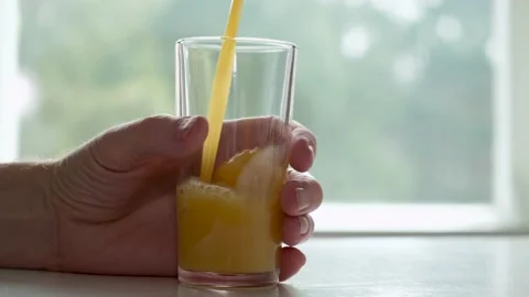 An empty glass in man's hand.Freshly squeezed orange juice is poured into glass. Stock Footage 152807869