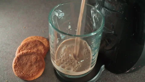 Empty glass sits beside cookies on a table and coffee being poured Stock Footage 337656234