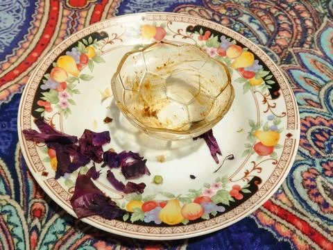Empty glass sits on a patterned plate. Stock Photos