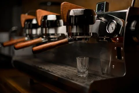 Empty glass on steel surface of professional coffee machine in coffee shop Stock Photos