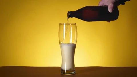 An empty glass is on the table, beer is poured into it. Stock Footage 196887455