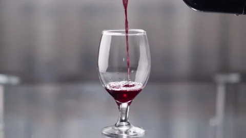 Empty glass on the table into which red wine is poured from a bottle Stock Footage 136330379