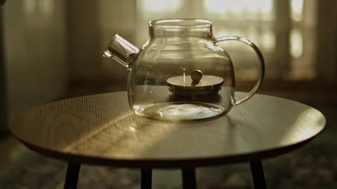 Empty glass teapot with loose tea leaves being added, backlit by window ligh Vidéo 346306273