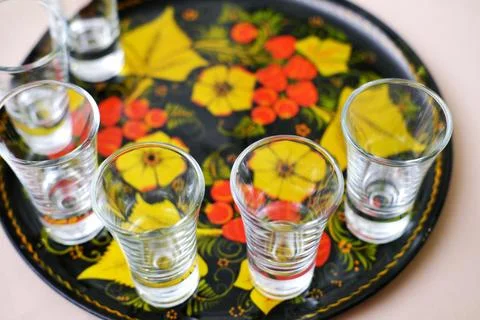 Empty glasses for alcohol stand on a tray painted in the old Russian style... Stock Photos