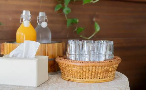Empty glasses setting in a wicker basket with orange juice and water in bot.. Foto stock