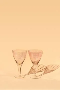 Empty glasses for wine stand on light background in sunlight with shadows. Stock Photos