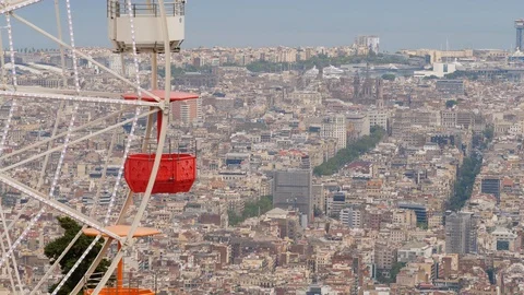 Empty gondolas of carousel wheel move against dense build city seen from height 스톡 동영상 100691556