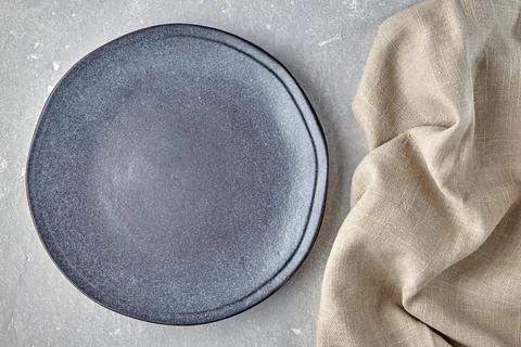 An empty gray ceramic plate and a rough linen napkin on a gray concrete tab.. Stock Photos