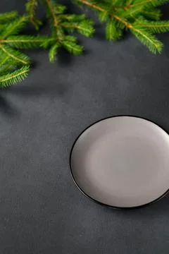 An empty Gray Ceramic Plate on a black table in the foreground. Green branche Foto stock