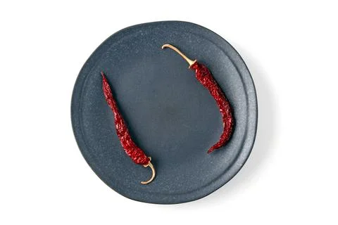 Empty gray ceramic plate with dried hot peppers isolated on white background Stock Photos