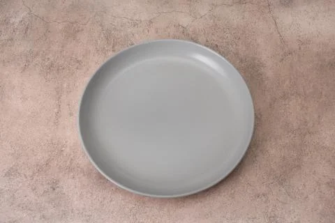 Empty gray ceramic plate with high rim placed on brown background. Flat lay.. Stock Photos