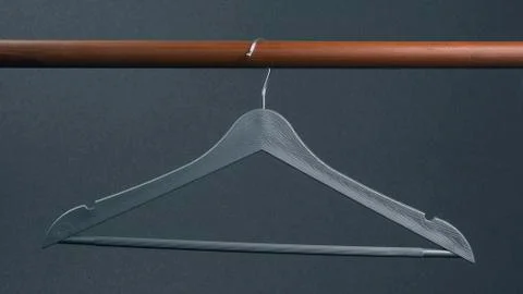 Empty gray plastic clothes hanger hanging on a dark background. Accessories a Stock Photos
