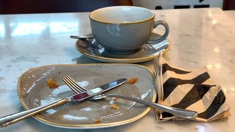 Empty gray plate rests with fork and knife, crumbs scattered after breakfast Stock Photos