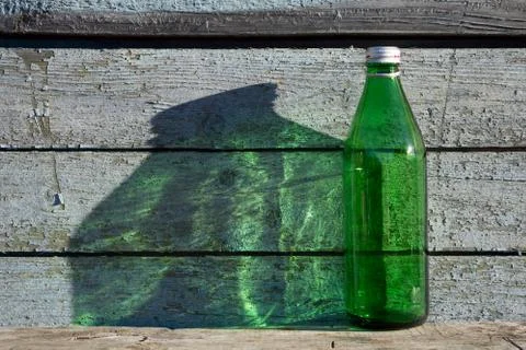 Empty green   bottle against wooden blue old wall on wooden table  under the  Stock Photos