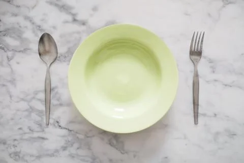 Empty Green Dish with Stainless Forks and Spoon, on White Marble Stone Table Stock Photos