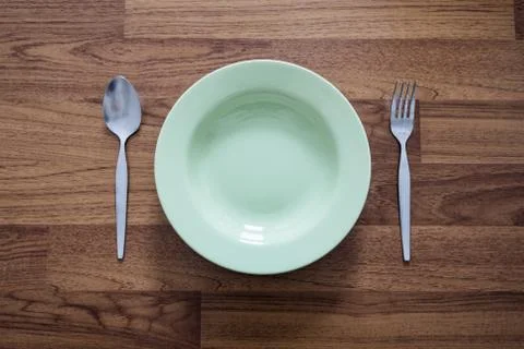 Empty Green Dish with Stainless Forks and Spoon, on Wood Texture Background Stock Photos