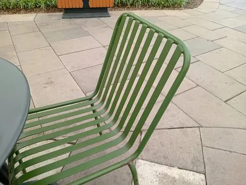 Empty green metal bench on paved outdoor area Stock Photos