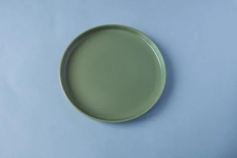 Empty green plate on blue background. Top view. Flat lay. Stock Photos