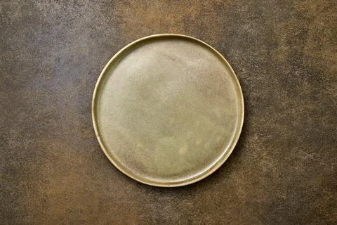 Empty green rustic ceramic plate with black rim on brown rustic background Foto stock