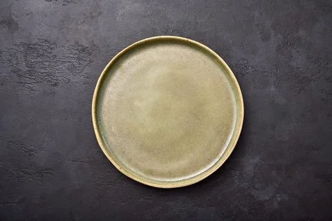 Empty green rustic ceramic plate with black rim on a dark textured graphite Stock Photos