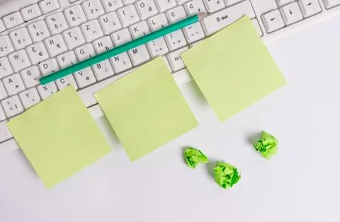 Empty green square papers and pencil by the pc keyboard with copy space. Flat Stock Photos