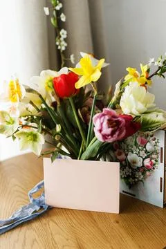 Empty greeting card, gift box and bouquet on wooden table. Happy Mother's d.. Stock Photos