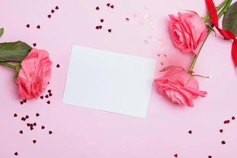 Empty greeting card on the pink table with roses nd small heart shaped confetti Stock Photos