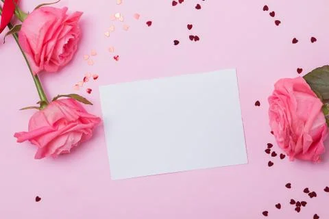 Empty greeting card on the pink table with roses nd small heart shaped confetti Stock Photos