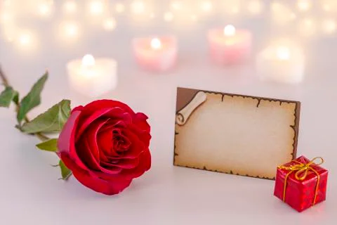 Empty greeting card with single red rose, gift box, and candles Stock Photos