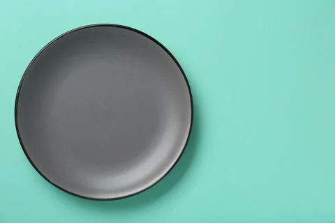 Empty grey ceramic plate on turquoise background, top view. Space for text Foto stock