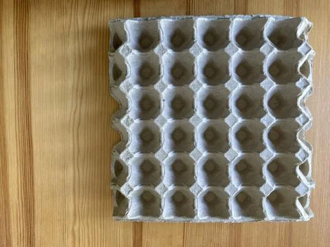 Empty grey paper egg tray on a natural light brown rubber wooden table Stock Photos