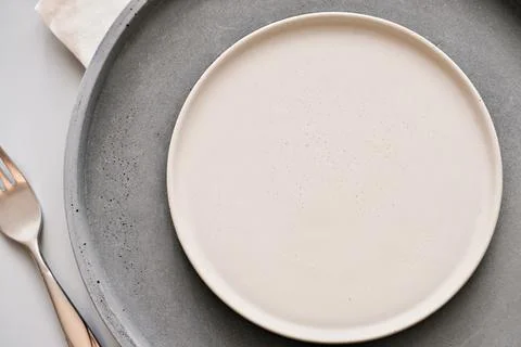 Empty grey plates on a table with fork and knife. spring menu concept. trendy Stock Photos
