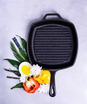 Empty grill pan on a kitchen table with cooking ingredients. Flat lay Stock Photos