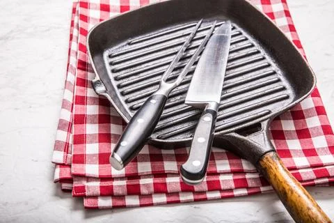 Empty grill pan on marble table with red tablecloth knife and fork Stock Photos