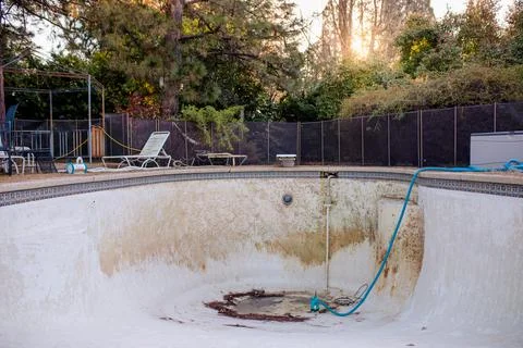 Empty In Ground Pool with Puddle and Repair Equipment in a Backyard Stock Photos