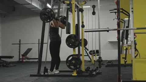 Empty gym, only one young woman doing squats in the Smith machine. Stock Footage 255308083