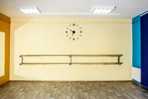 Empty hall dance hall with clock on the wall and ballet bench for training Stock Photos