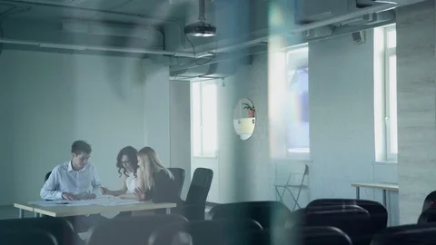 In the empty hall three staff at the table look the paper and talk Stock Footage 72536837
