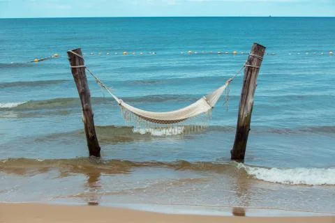 Empty hammock between palm trees on tropical beach Stock Photos