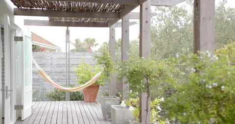 Empty hammock hanging on wooden deck in peaceful backyard garden, copy space Stock Footage 297930051